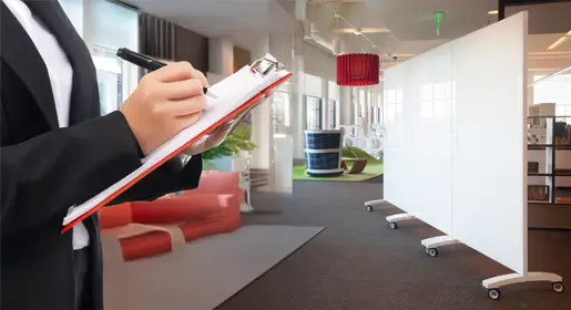 Hexagonal acoustic wall tiles in cool colors arranged as a striking geometric feature wall behind a casual lounge with sofas and coffee tables in a naturally lit office. Combines style with superior noise absorption