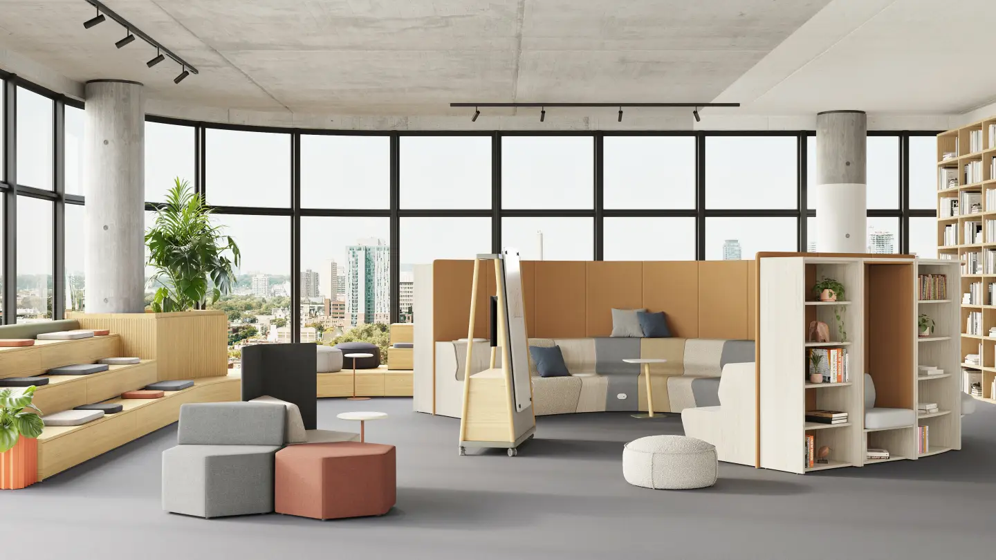 Modern university commons with tiered wood bleacher seating, modular privacy pods, curved upholstered sofa walls, mobile whiteboard, ottomans, and open bookcases for collaborative student lounging and group study.