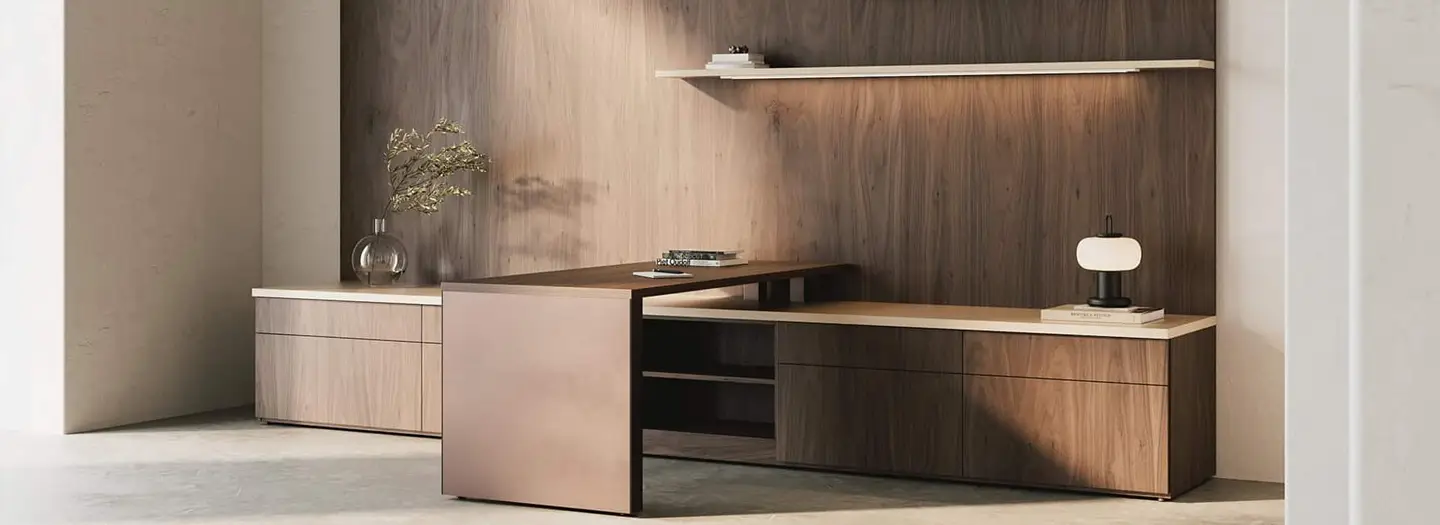 Executive private office with rich walnut L-shaped desk, integrated credenza, floating illuminated shelf, modern task lamp, and minimalist wood panel wall for focused leadership workspace.