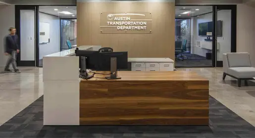 Elegant Central Park reception desk with mixed exotic veneer and stone materials, placed centrally for impact in a client-facing reception space