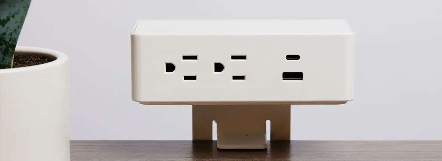 Close-up of white DEKKO power and data outlet from Office Furniture Connection – sleek surface-mounted unit with USB and AC outlets for easy attachment to any worksurface or desktop.