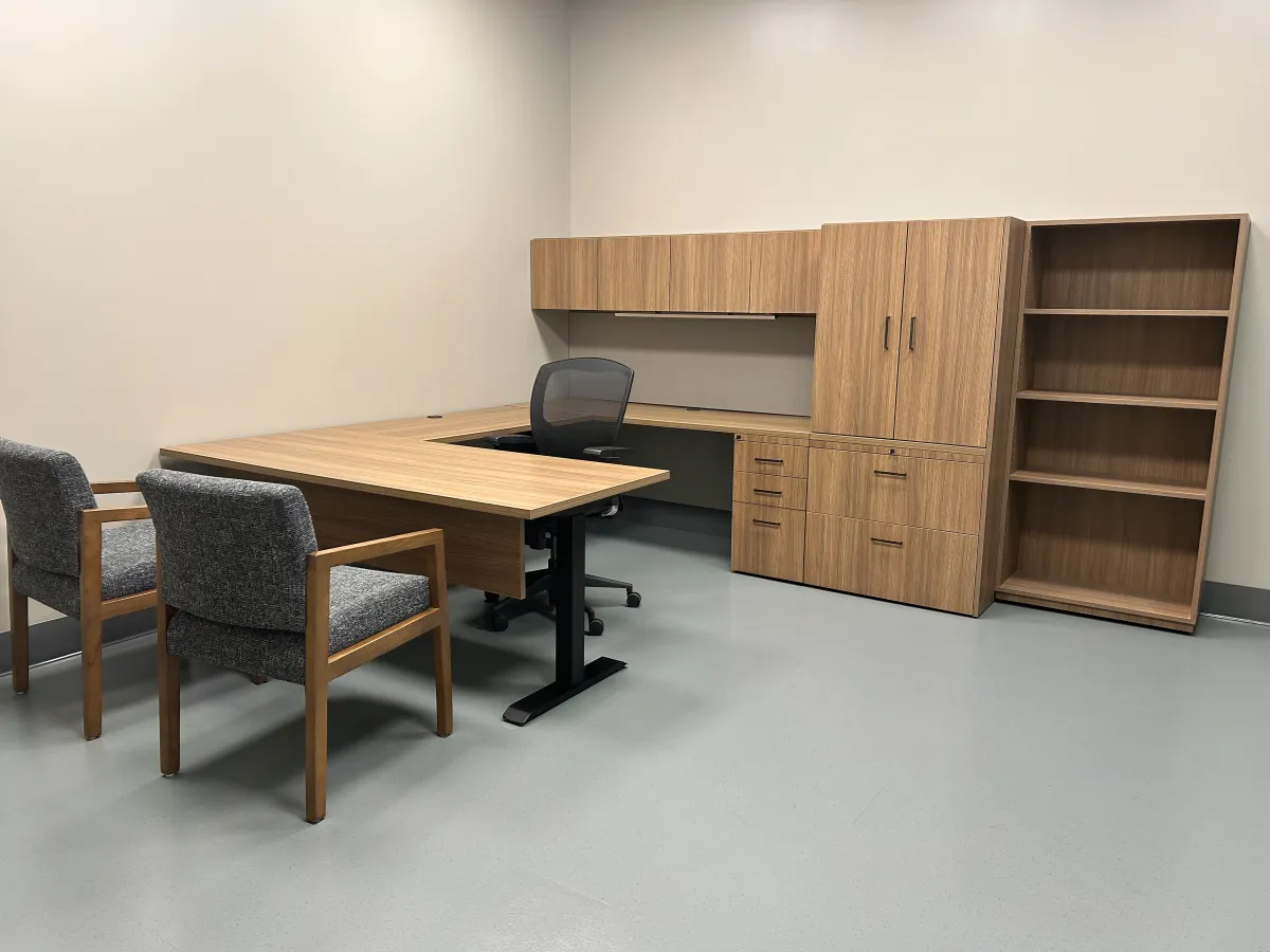 Contemporary modular private office setup from OFC CONNECT series featuring oak wood laminate U-shaped adjustable height desk with modesty panel, integrated power outlets, overhead storage cabinets, lateral filing, box box file pedestal and two upholstered guest chairs for collaborative efficiency – affordable executive workspace solutions by Office Furniture Connection Houston TX.