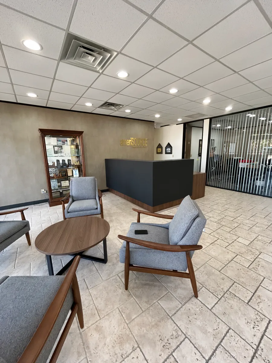 Inviting reception area with OFC CONNECT Series walnut and charcoal laminate corner desk, and comfortable guest seating under branded wall logo – complete professional lobby reception packages by Office Furniture Connection Houston TX.