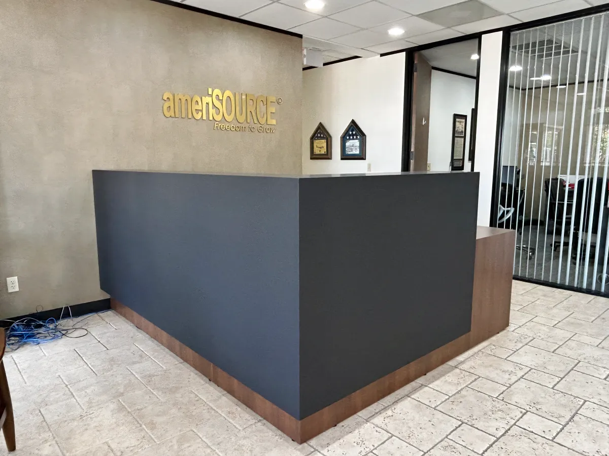 Bold charcoal and walnut wood laminate reception desk from OFC CONNECT Series with elevated transaction top, clean geometric design, and ADA-compliant height options – striking modern front office solutions delivered by Office Furniture Connection Houston TX.