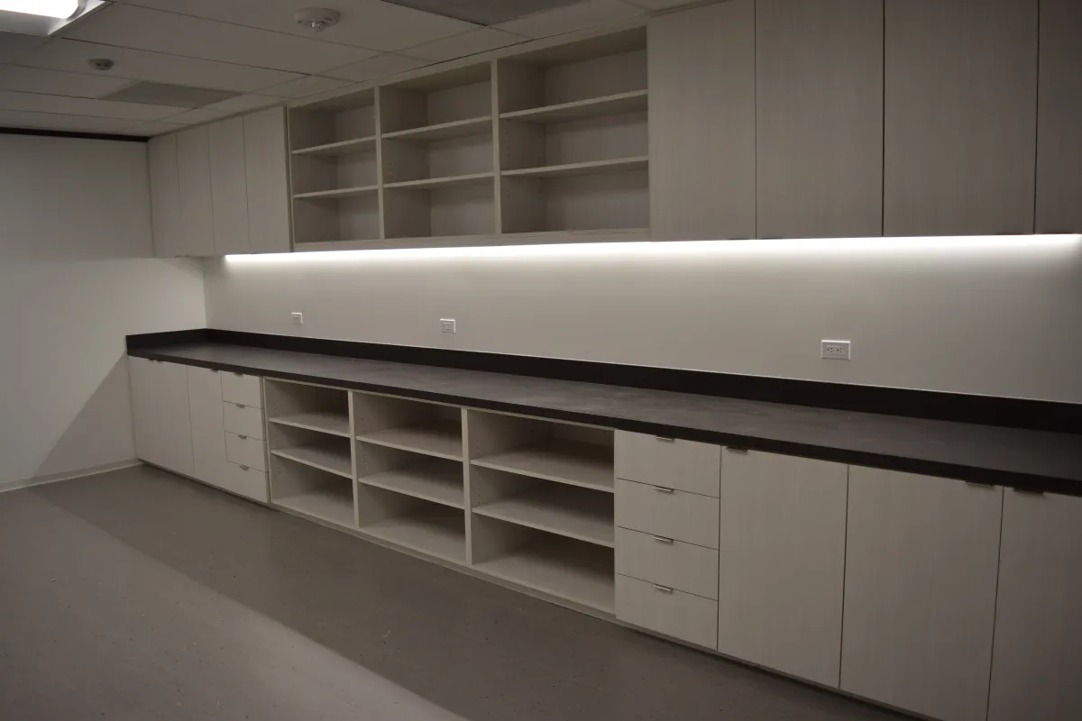 Contemporary wall-mounted storage run from OFC CONNECT Series in light grey laminate with black laminate countertop, open cubbies, under-cabinet LED lighting, and full-height cabinets – sleek breakroom and office organization furniture by Office Furniture Connection Houston TX.