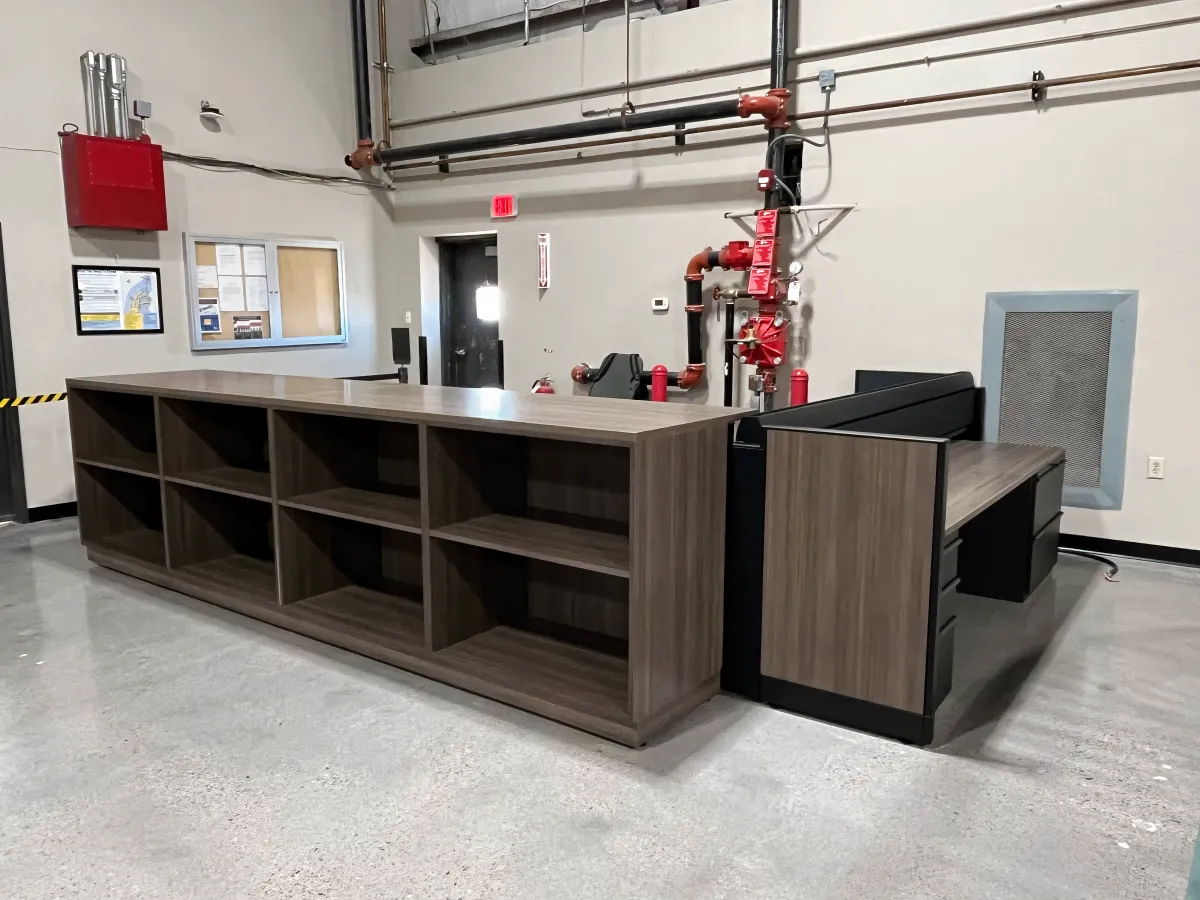 Versatile, cleanable, large wood laminate open storage unit to match adjacent Knoll Morrison workstation with pedestal filing in a warehouse environment.