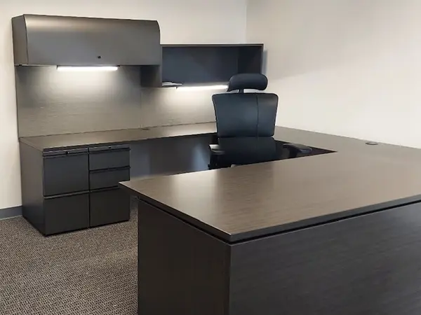 CONNECT Blend private office with U-shaped executive desk, ergonomic task chair, overhead storage and guest seating – complete modern workstation solution in dark wood-tone laminate, two undersurface pedestals and two overhead storage units. Black leather executive task chair