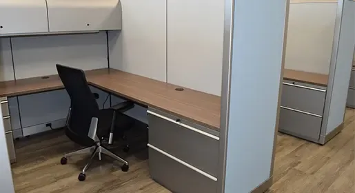 Knoll Morrison workstations with 64" grey fabric panels, grey 2 drawer lateral files and file/file. Overhead storage is also grey and lockable. Worksurface are medium wood laminate with a black task chair with chrome base.