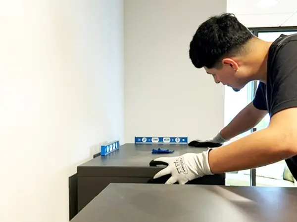 Professional technician in gloves meticulously cleaning and installing premium pre-owned lateral files in bright workspace– expert delivery and installation services ensuring sustainable decommissioned furniture is move-in ready for your office.