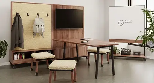 Warm nonprofit breakout space with walnut media wall and table, mobile upholstered stools and large mobile markerboard with laminte wood trim – high-quality refurbished furniture creating versatile, comfortable areas for informal gatherings and staff recharge.