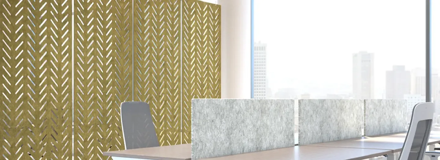 A downtown office with a 6 pod of benching furniture. Behind this is a 'wall' of accoustic panels in mustard yellow with a herringbone type pattern to absorb sound in the workspace.