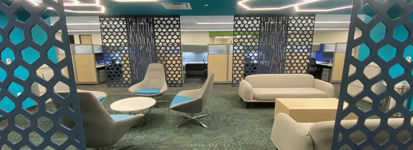 Accoustic panels enclose a public seating area with comfortable guest seating and sofas between work areas with cubicles