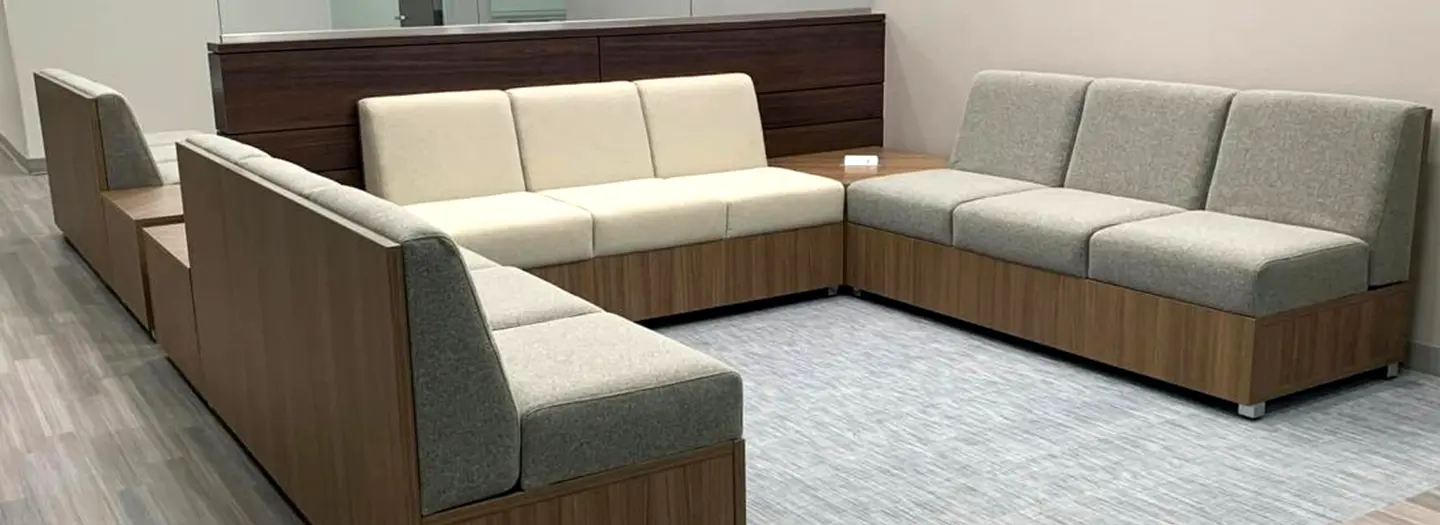 Modular lounge seating in a U-shpae for customers to enjoy with wood backs and base topped with large seat and back cushions sold through OFC. End table are a wood laminate.
