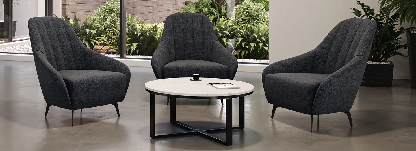 An occasional table takes center stage in a reception area surrounded by three lounge chairs.