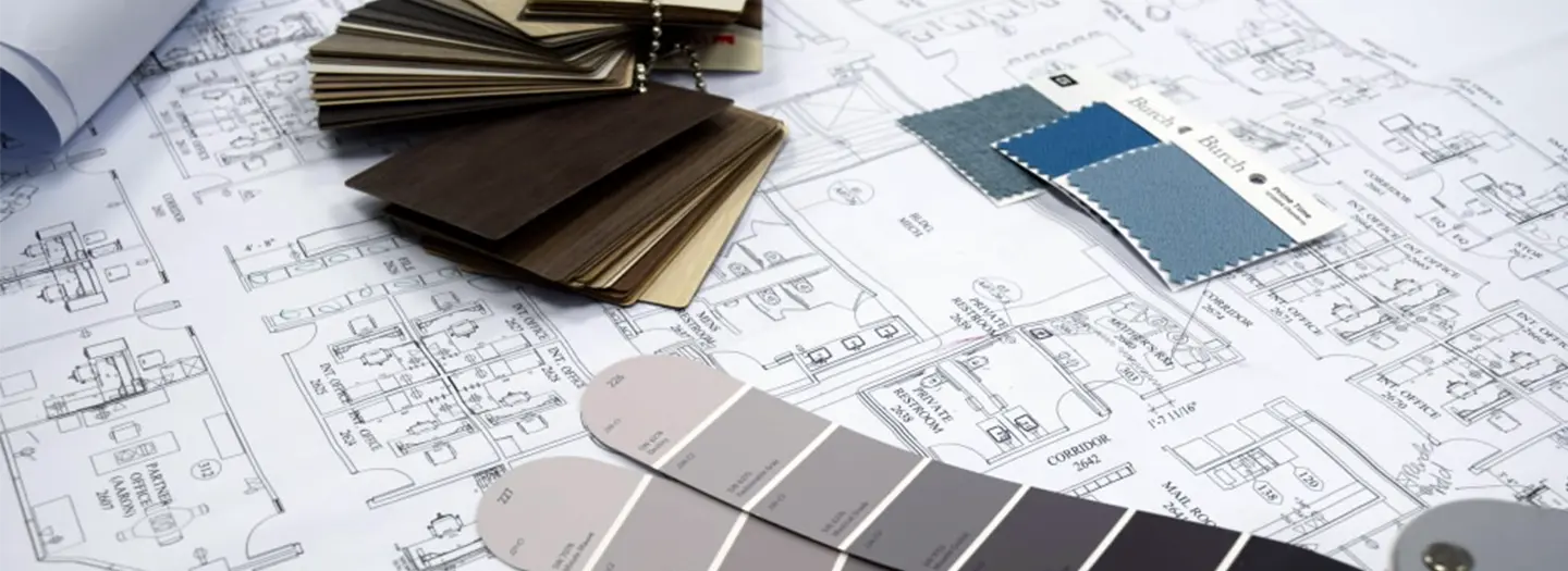 Close up of floor plans on a horizontal surface with paint deck and wood samples scattered across them.