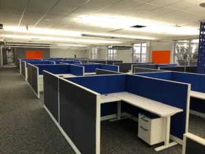 Remanufactured Knoll Morrison workstations with 42H navy/charcoal panels, L-shaped height-adjustable desks, and upholstered mobile box/file pedestal in a spacious open office with natural light. Ideal for flexible corporate layouts.