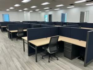 Remanufactured Knoll Morrison workstations with navy blue 48H panels, light-tone wood laminate desks, mesh back task chairs, and box/box/file storage in a modern showroom with wood-look flooring. Perfect for scalable corporate offices.