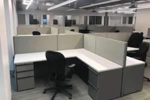 Remanufactured Knoll Morrison cubicles with neutral gray 48H panels, white L-shaped worksurfaces, refurbished ergonomic Steelcase chairs, box/box/file and fiile/file pedestals in a professional open-plan office. Affordable high-quality office solution.