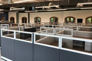 Large group of clean remanufactured Knoll Morrison 6x6 cubicles with 56H panels and glass stackers arranged in pods inside a high-ceiling warehouse with exposed ducts. Turnkey solution for 50+ employee office layouts.