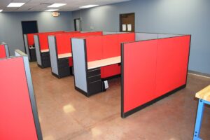 Open layout of Knoll Morrison remanufactured workstations featuring 56H red and blue panels, spacious white worksurfaces, and box/box/file storage in a modern warehouse with natural light. Perfect for companies seeking premium used office furniture.