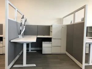 Remanufactured Knoll Morrison open workstation with 48"h gray fabric and 16"h glass panels, white adjustable height desk with return and dual monitor arm, open shelving, filing pedestals, and wardrobe storage to maximize storage for employees.