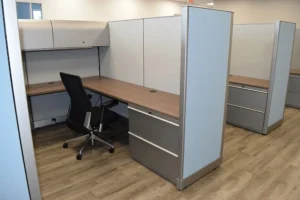 Row of remanufactured Knoll Morrison cubicles with 64"h blue and gray panels, wood-tone worksurfaces, overhead lockable storage with task light, lateral filing, and ergonomic chairs on wood-look flooring.
