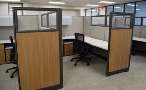 Row of remanufactured Knoll Morrison workstations with 64" dark gray fabric panels with 16" glass at top and silver name plates. Graphic mulit colored grey and yellow carpet with dark grey sled base sige chairs for privacy and quiet conversations.