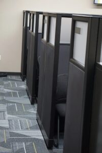 Row of remanufactured Knoll Morrison workstations with 64" dark gray fabric panels with 16" glass at top and silver name plates. Graphic mulit colored grey and yellow carpet with dark grey sled base sige chairs for privacy and quiet conversations.