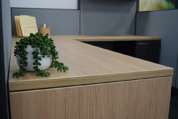 Close up of a high quality new wood laminate worksurface edge in a Knoll remanufactured cubicle with blue fabric panels