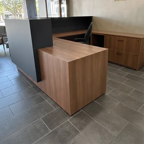 New CONNECT custom reception desk from Office Furniture Connection featuring a bold black counter, darker wood laminate worksurfaces, and matching lateral files in a modern office entryway.