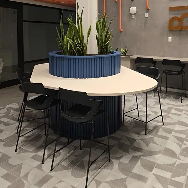 New CONNECT series round collaborative high-top table with black bar stools around large blue planter filled with lush greenery in open modern lounge with geometric tile floor – new office breakout and collaboration furniture for sale Houston TX at Office Furniture Connection.
