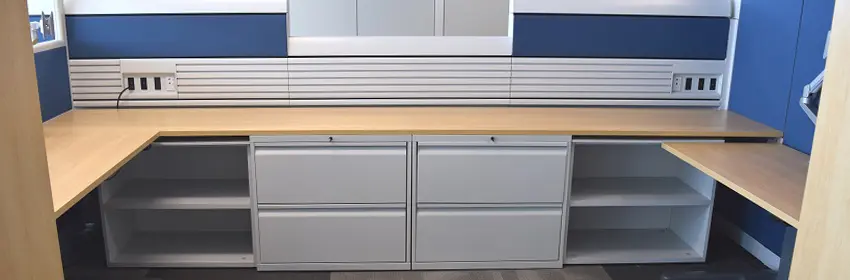 Two Knoll Currents workstations with blue panels and oak wood laminate worksurfaces and filing laterals below.