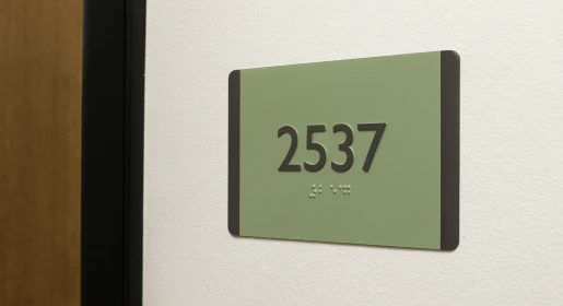 2-90 Compliant Flexible Signs ADA-compliant interior room identification sign with sage green panel, raised tactile numerals 2537 and Grade 2 Braille – modern accessible office door signage solutions from Office Furniture Connection Houston TX.
