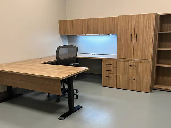 CONNECT Custom U-shaped private office with sit stand desk, modesty panel, lateral filing, overhead storage with task light and fabric covered tackboard. Open shelving and storage wardrobe in wood laminate. Unlimited options through the millwork shop at OFC