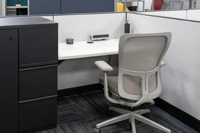 A remanufactured Knoll light gray fabric cubicle with 42 inch high panels, a white worksurface, and black storage unit with drawers, filing, and a small locker.