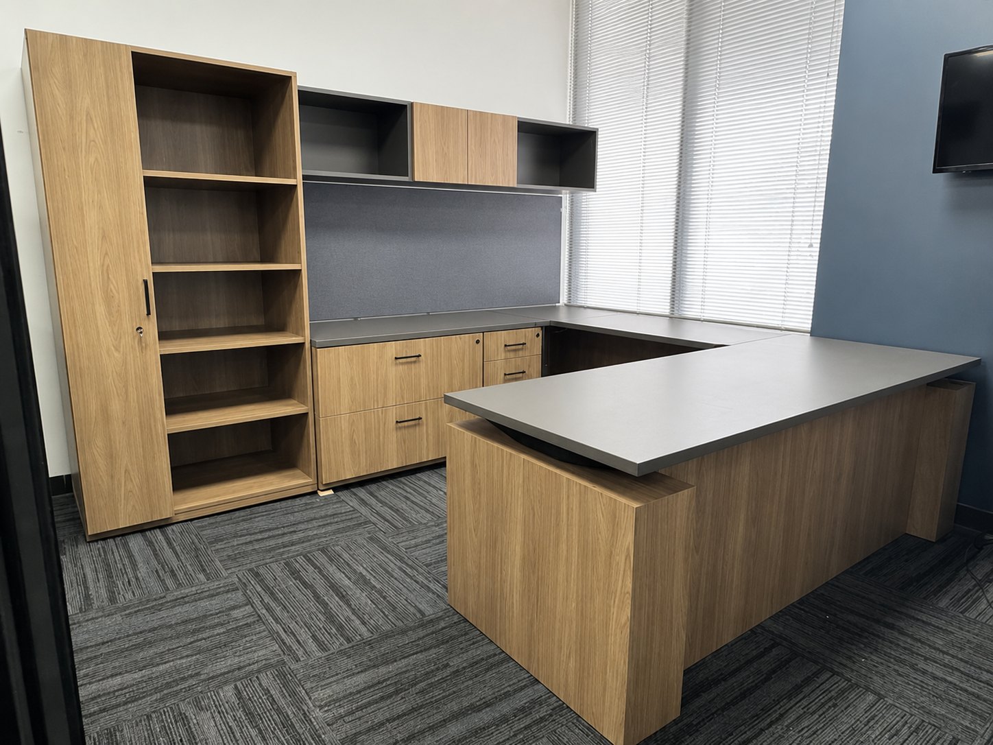 Two-tone U-shaped desk in our Houston showroom with wardrobe, tall bookcase, lateral files, overhead cabinets and sit-stand base