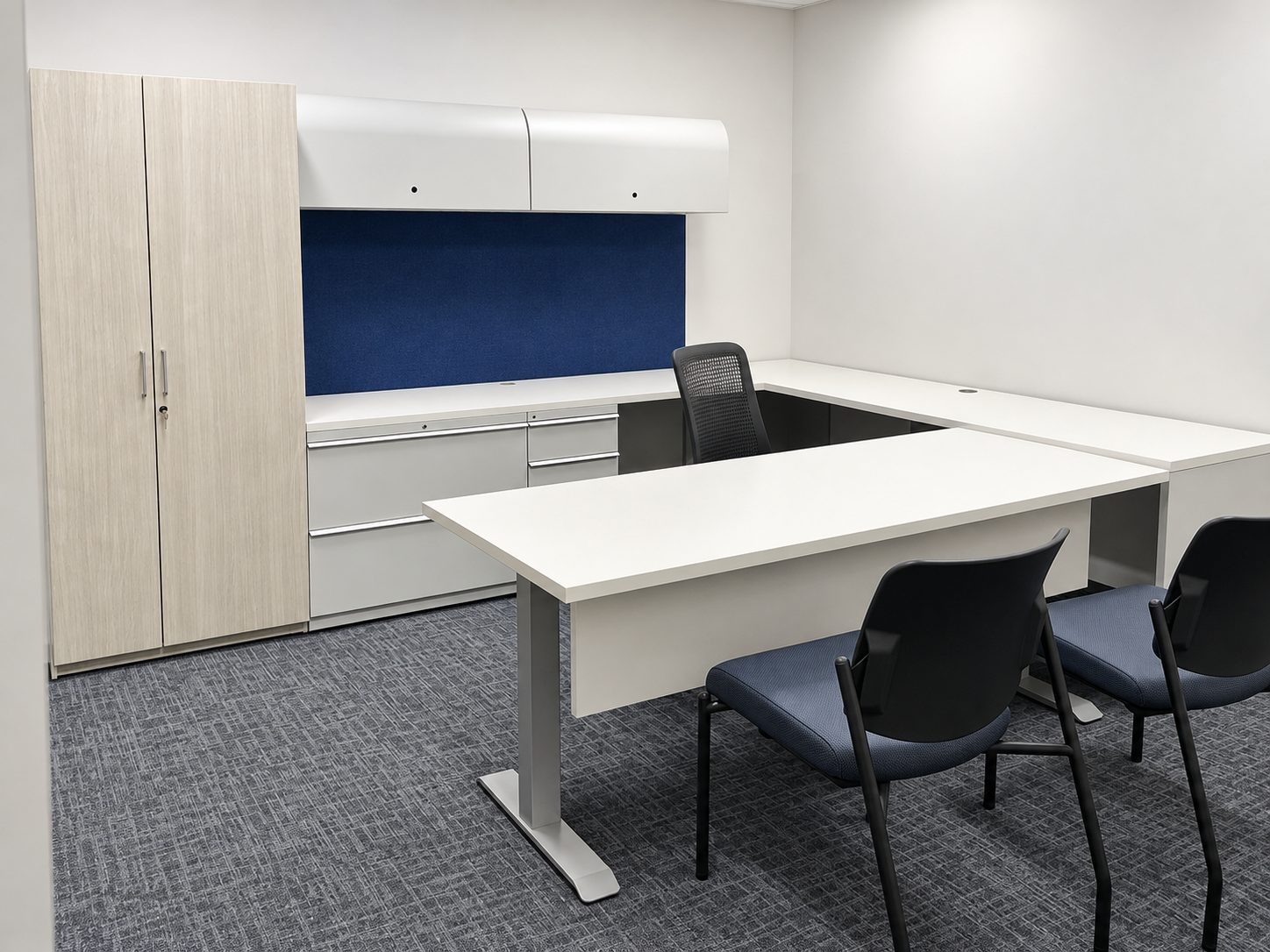 Private office with U-shaped desk, wardrobe cabinet, overhead storage and guest chairs at Rice University Police and EMS annex