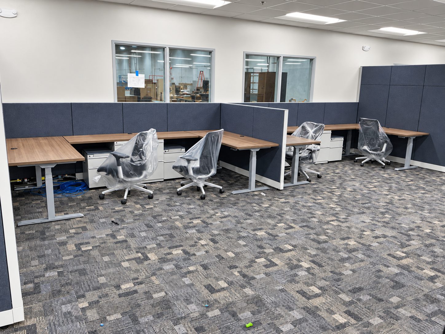 Open workstations with height-adjustable desks and pre-owned task chairs bagged for dust protection during construction