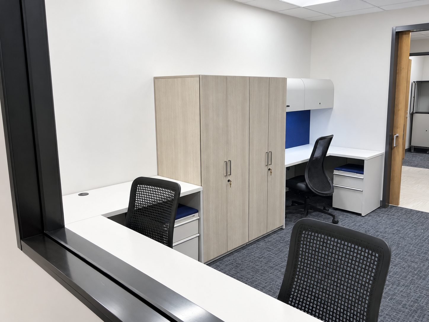 Shared office with two workstations, wardrobe cabinets and overhead storage for Rice University police staff