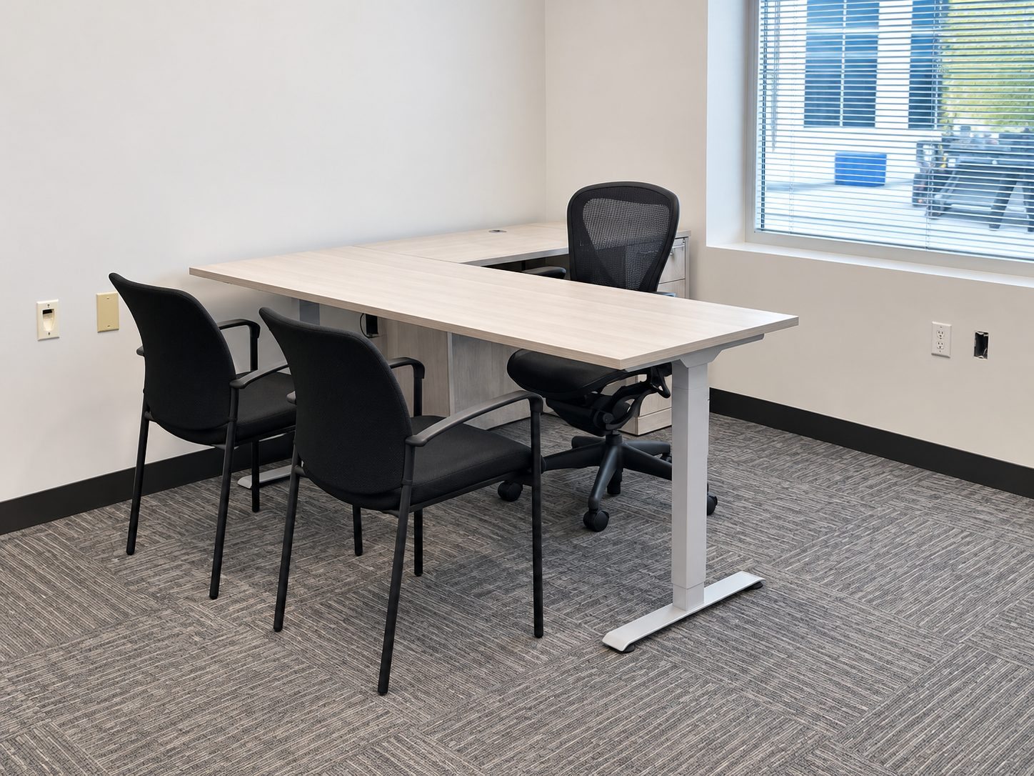 Private office with L-shaped height-adjustable desk, Herman Miller Aeron chair and guest chairs