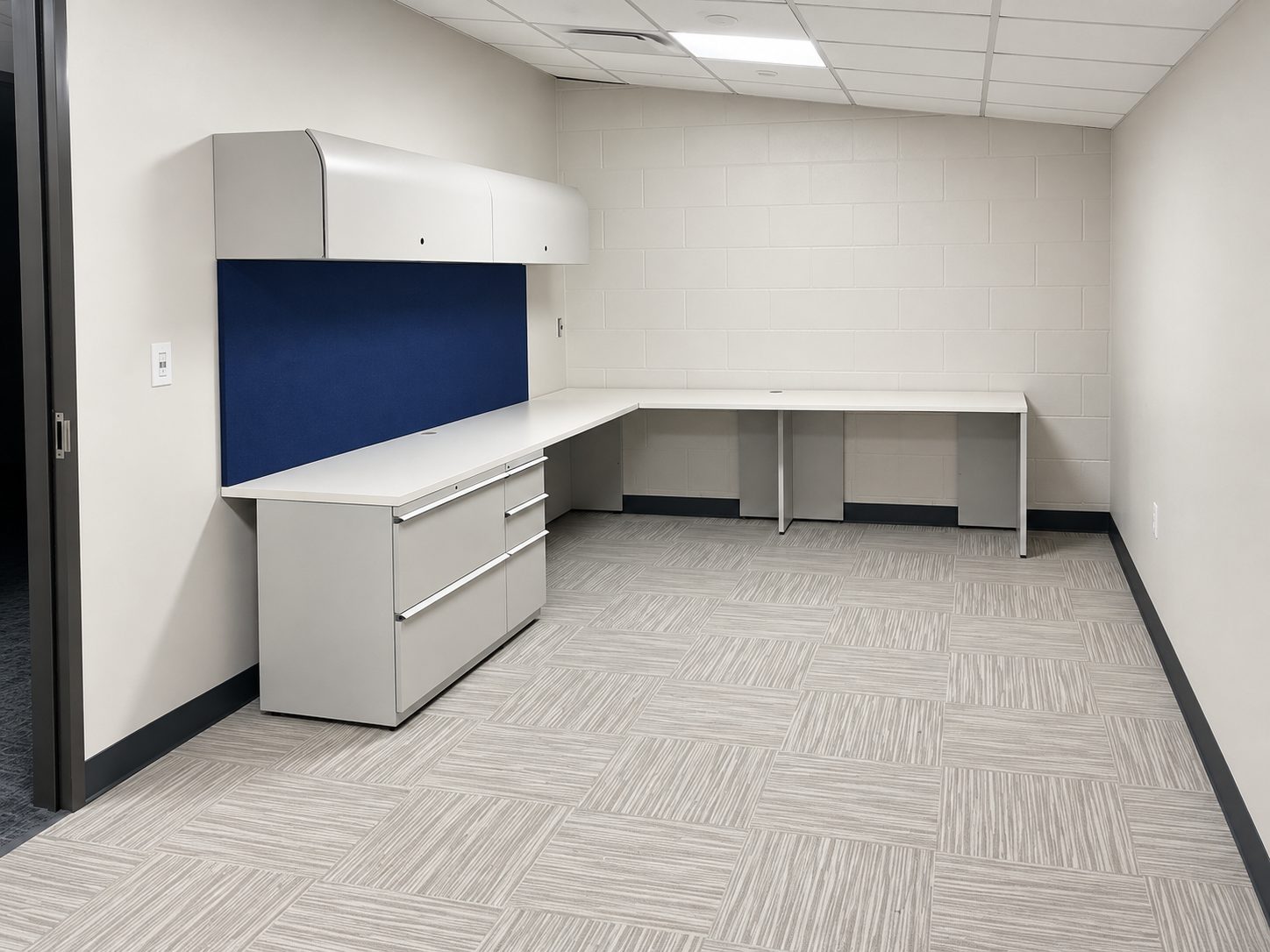 L-shaped workstation with lateral file and overhead storage in a Rice University Police office