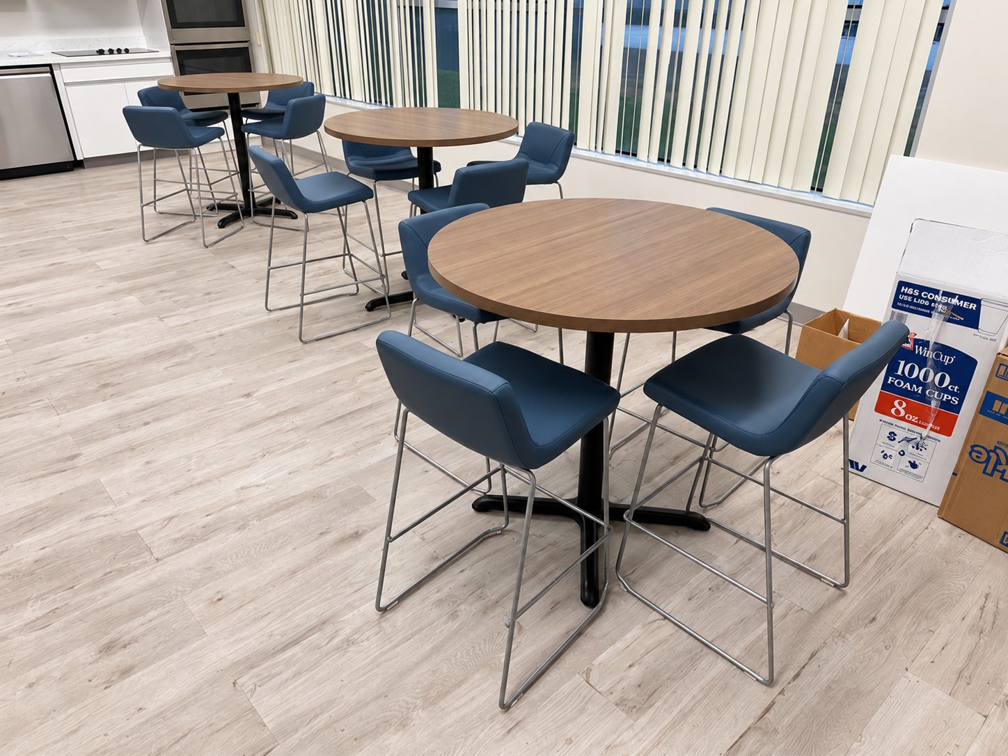 Break area with round bistro tables and blue upholstered stools