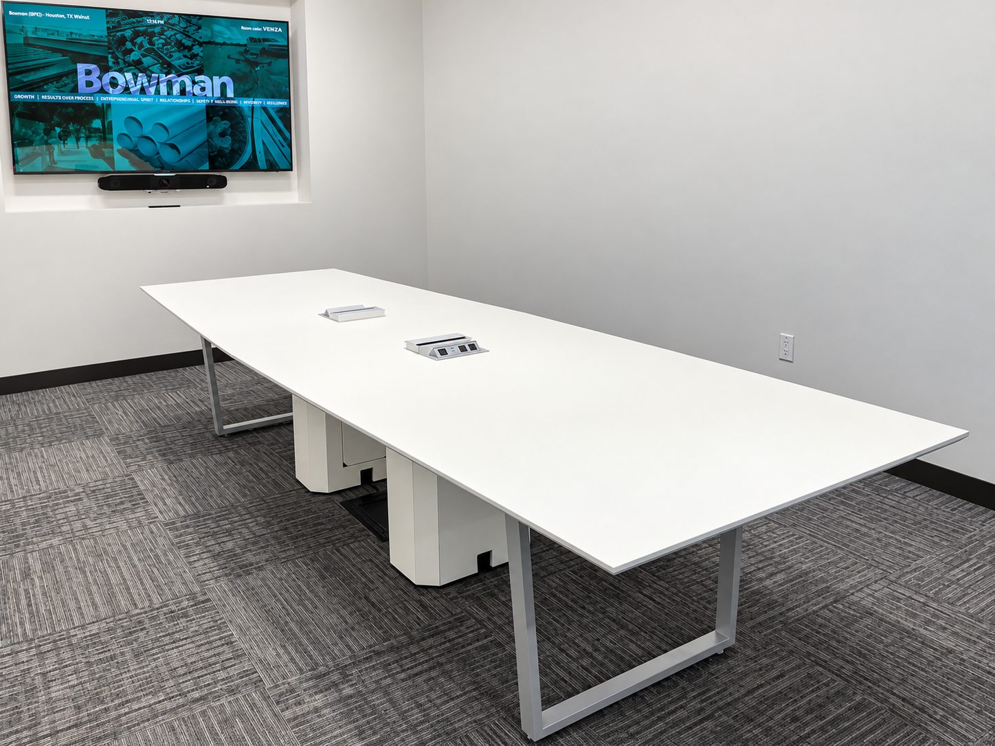 Large white conference table with power modules and sled base legs