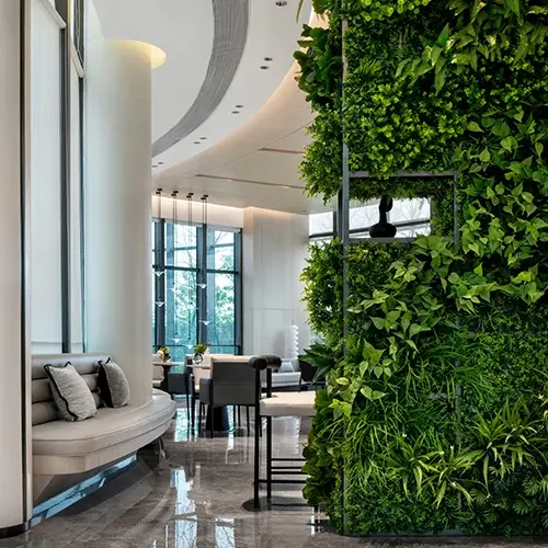 Bright, modern open space with white interiors, light wood and white tables, curved banquettes, bar seating and lush green living wall in a sunlit atrium. Sustainable liquidation for reuse of furniture like this and much more keeps premium furniture in circulation instead of landfills.