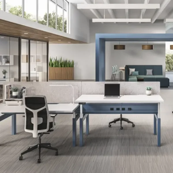 New furniture in an airy open 2 story office with full length windows on the right. New office furniture includes blue and white benching systems with acoustic privacy panels and white and grey ergonomic task chairs. Office Furniture Connection provides new furniture with warranties from trusted partners.